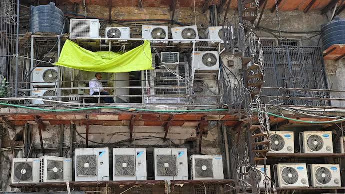 A man sits in a balcony amid air conditioning units installed on the facade of a building in New Delhi. (Photo: AFP)