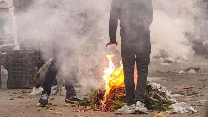 People warm themselves at a burning heap of waste. (Photo: PTI)